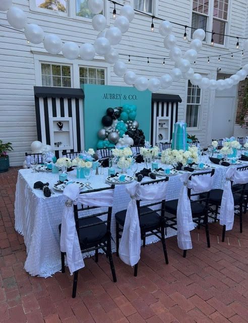 Tiffany & Co.-themed party setup with a long table, decor in blue, black, and white. Balloons and elegant setting.