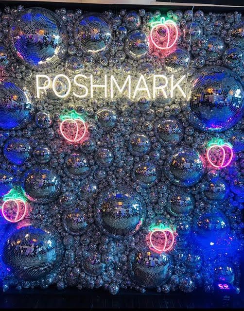 Poshmark sign in neon above a wall of mirrored spheres with glowing pink/green peach outlines.