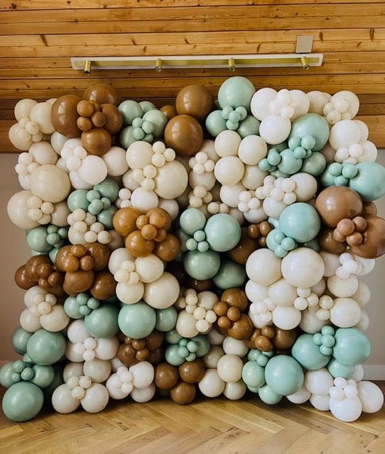 Balloon wall in neutral tones: brown, beige, and mint green, against a wooden background.