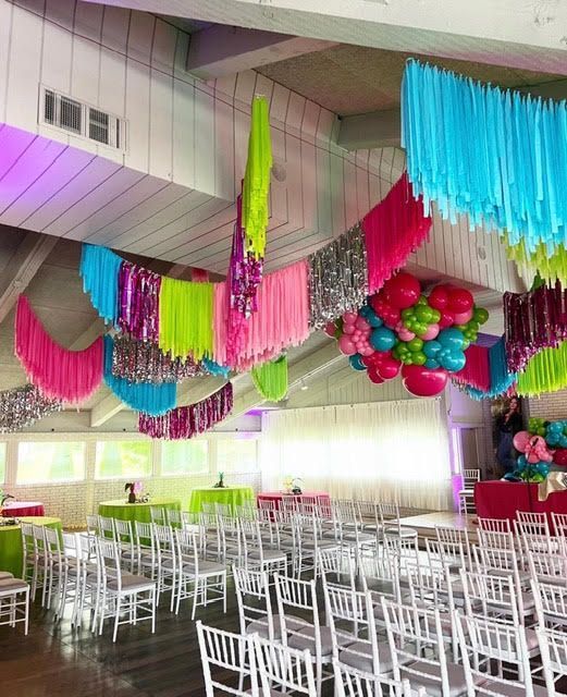 Event venue decorated with bright pink, green, and blue streamers hanging from the ceiling.