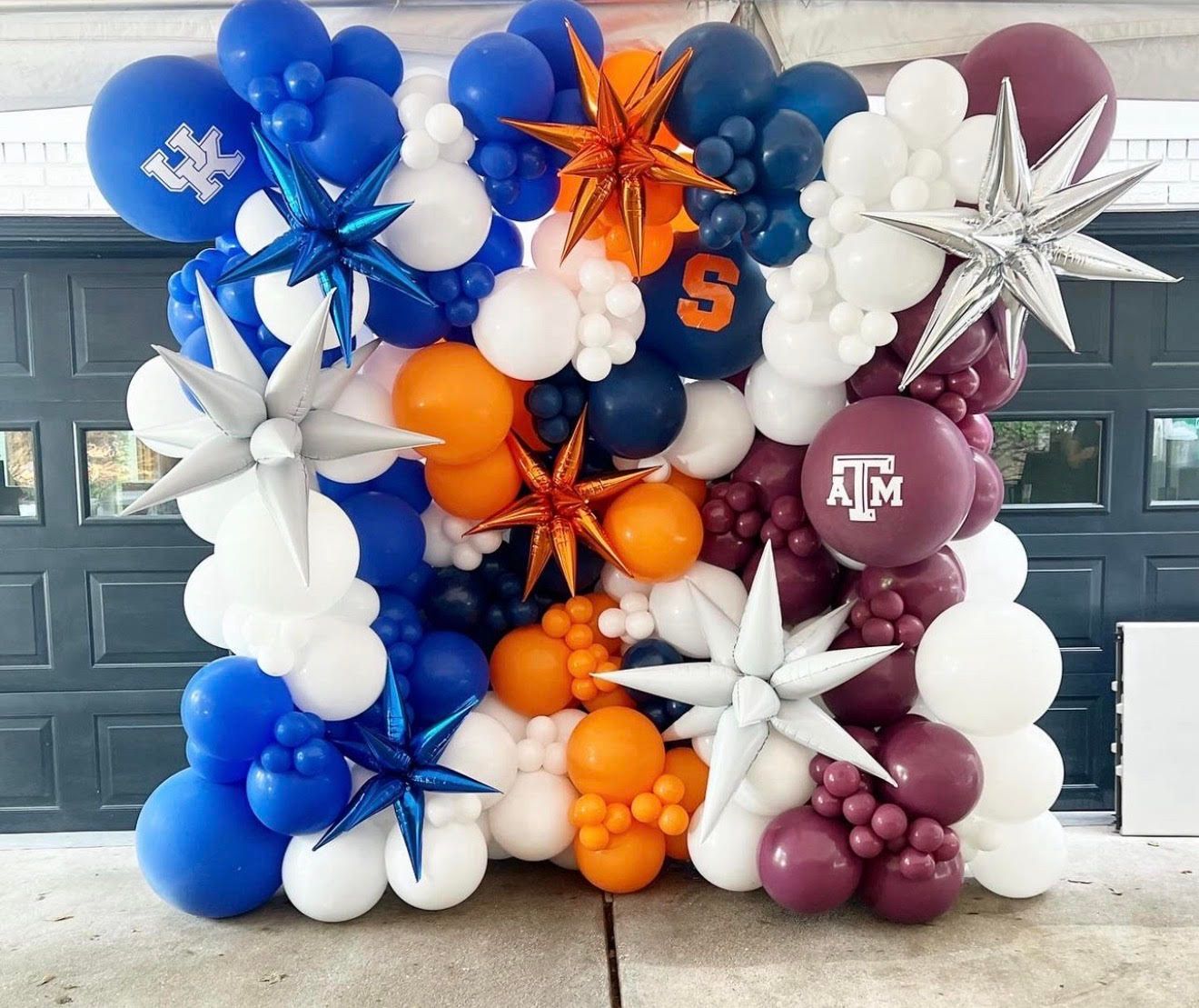 Balloon wall with sports team colors: blue, orange, white, and maroon with star decorations.