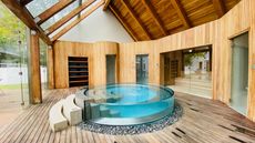 A luxurious circular indoor pool surrounded by wood and glass.