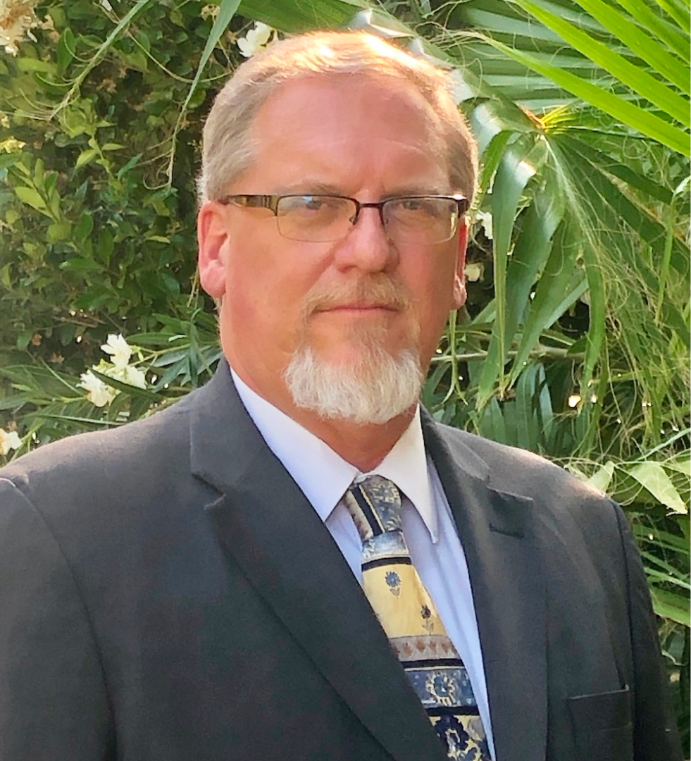 A man with a beard and glasses is wearing a suit and tie.