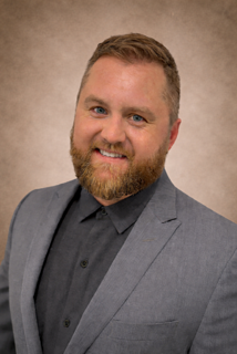 A man with a beard wearing a blue suit and red tie