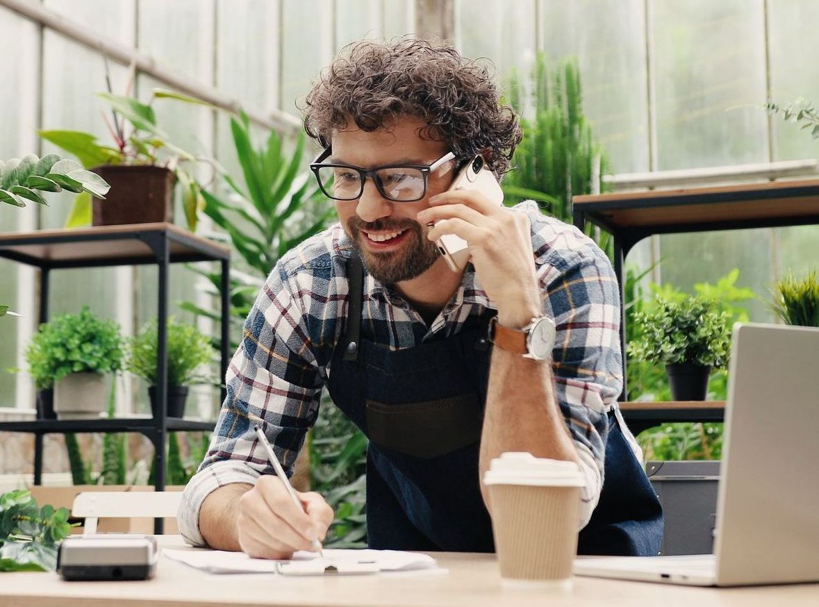 A man is sitting at a table talking on a cell phone.