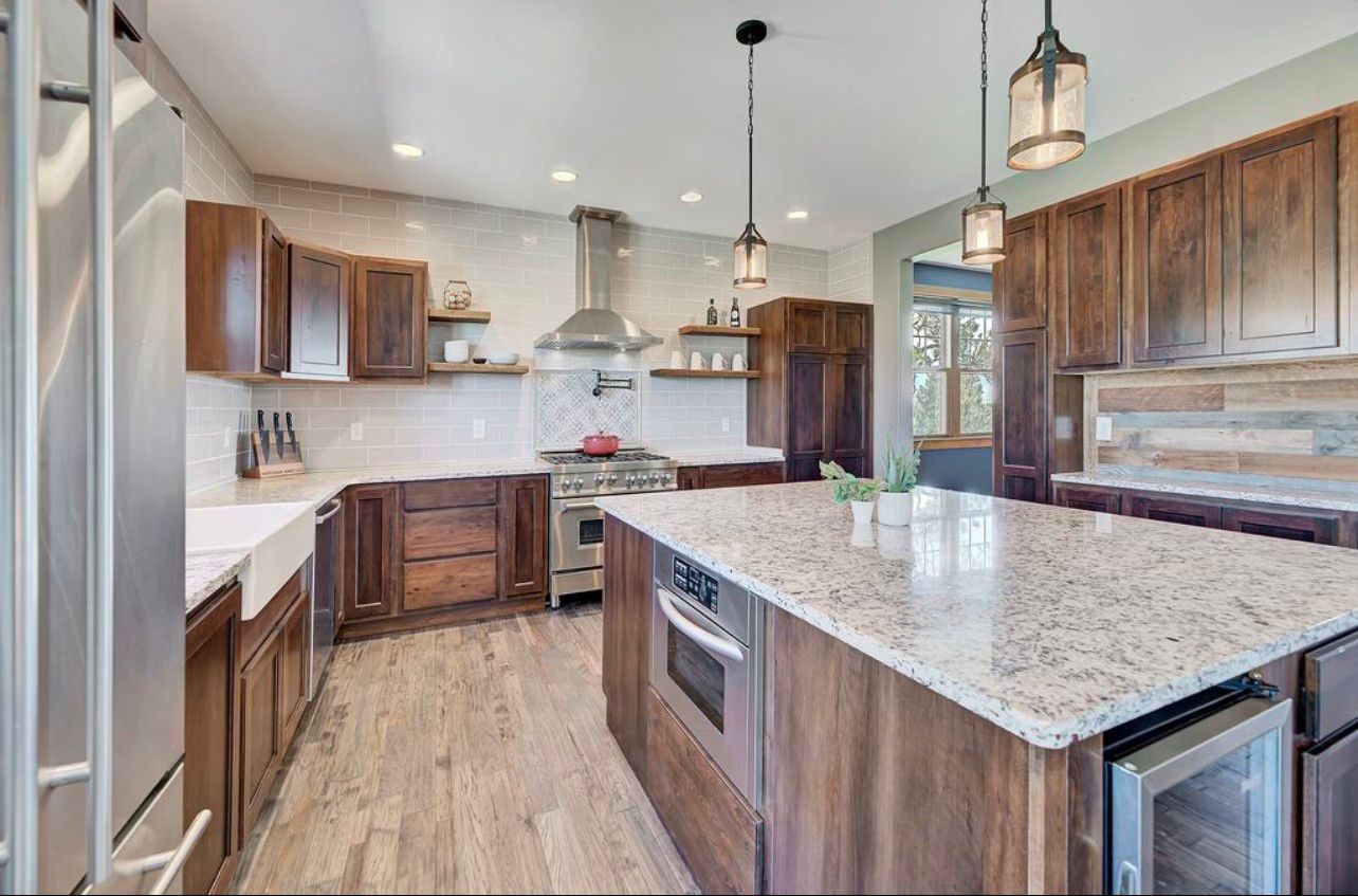 A kitchen with granite counter tops , stainless steel appliances , wooden cabinets and a large island.