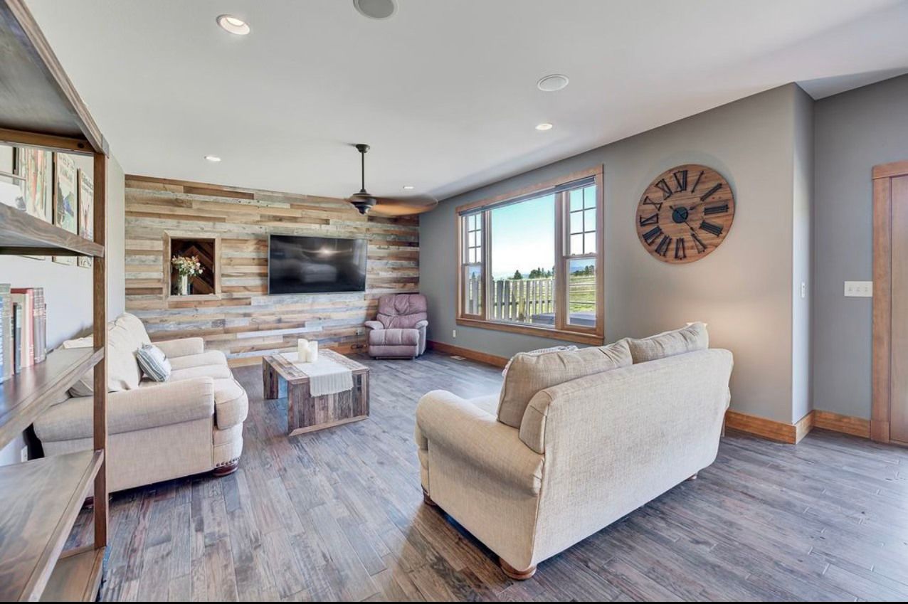 A living room with a clock on the wall and a couch.