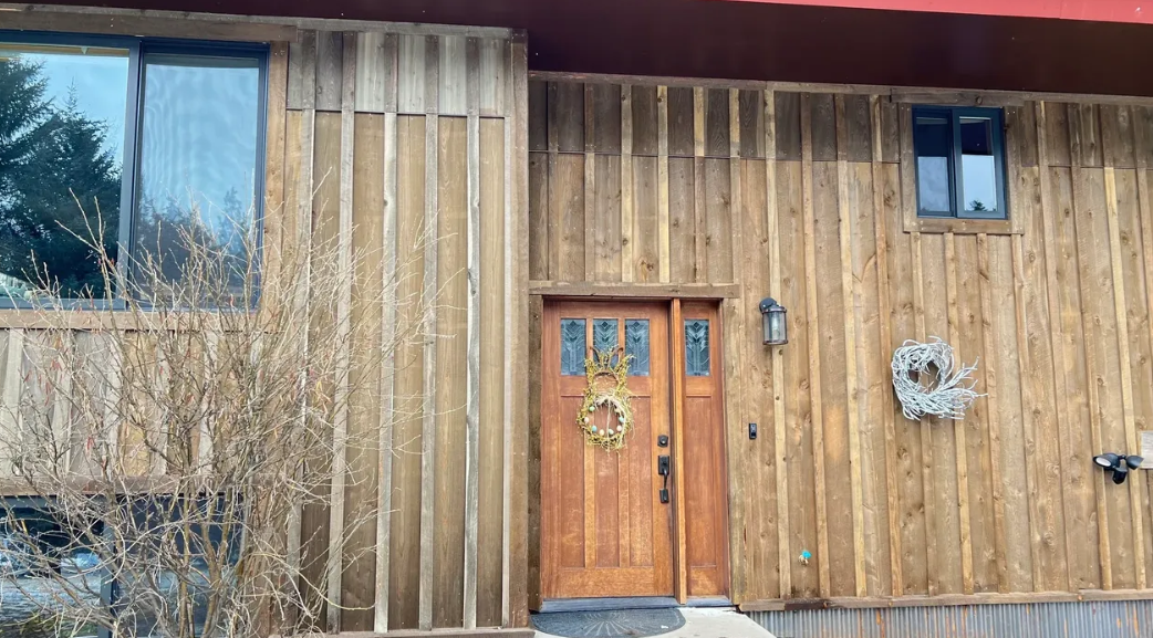 The front of a wooden house with a wooden door and windows.