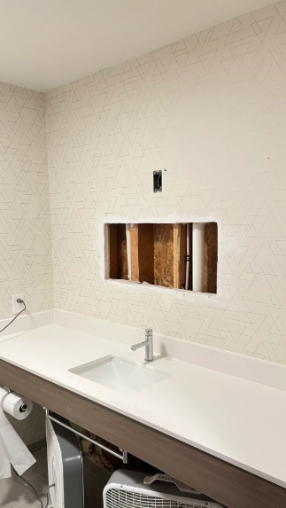 A bathroom with a sink and a hole in the wall.