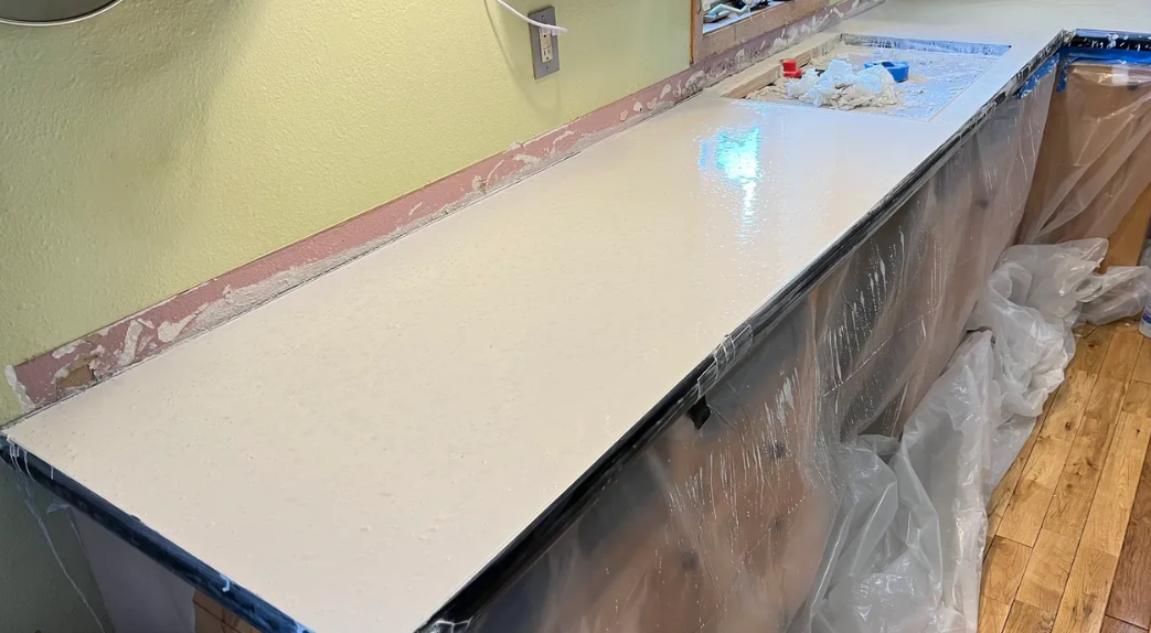 A white counter top is being painted in a kitchen.