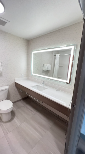 A bathroom with a toilet , sink and mirror.