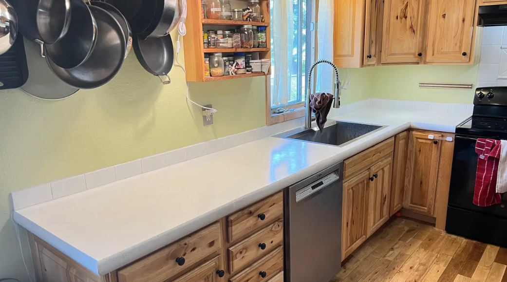 A kitchen with wooden cabinets , a sink , a stove , and a dishwasher.