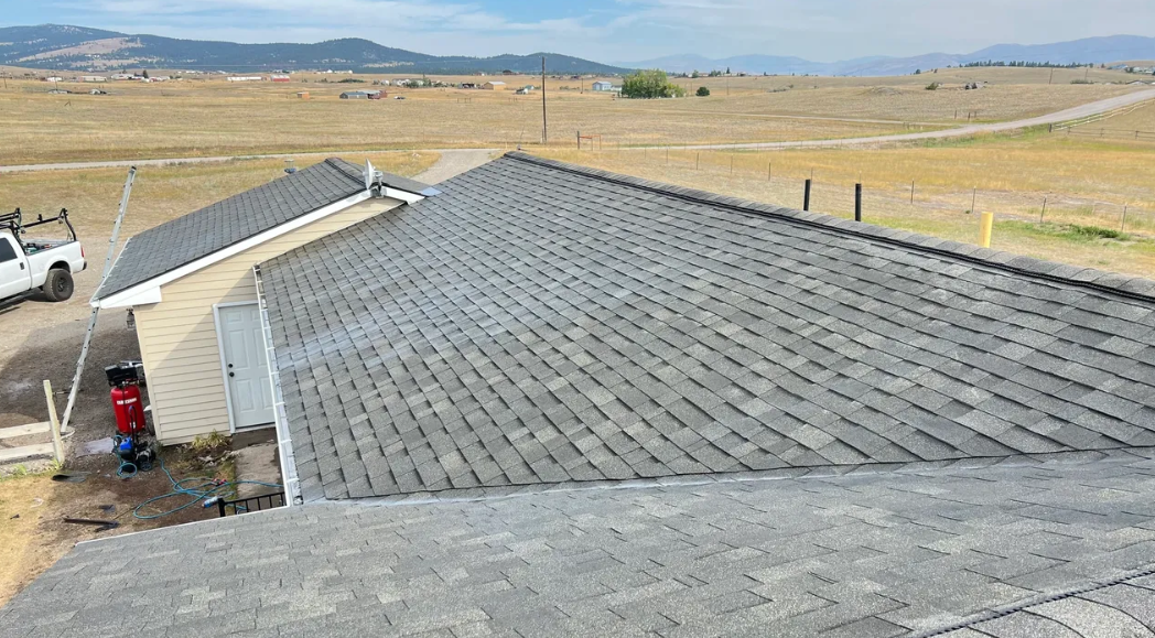 A house with a roof that is being built in the middle of a field.