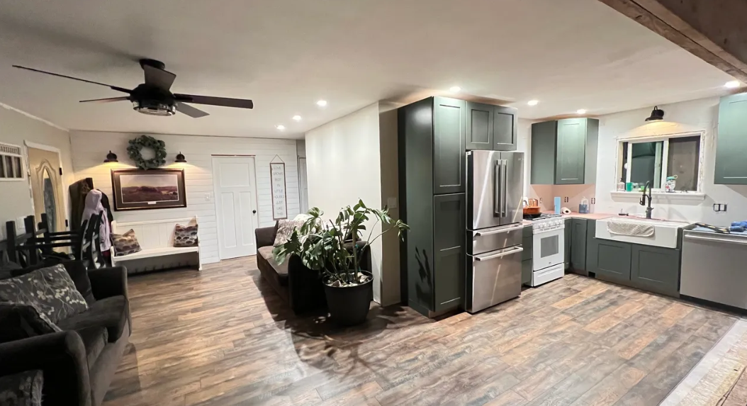 A living room and kitchen in a house with a ceiling fan.