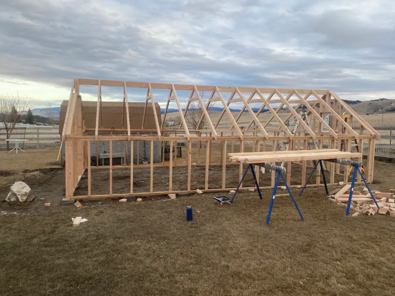 A greenhouse is being built in a grassy field