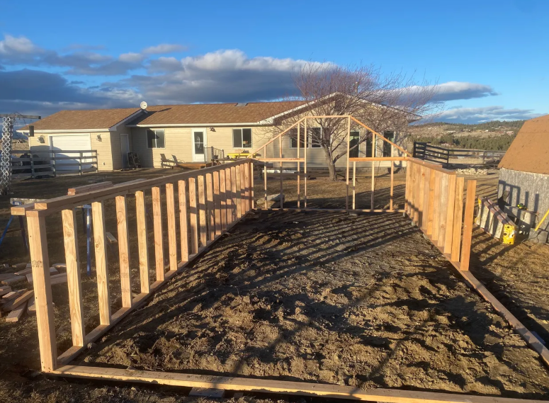 A wooden fence is being built in front of a house.