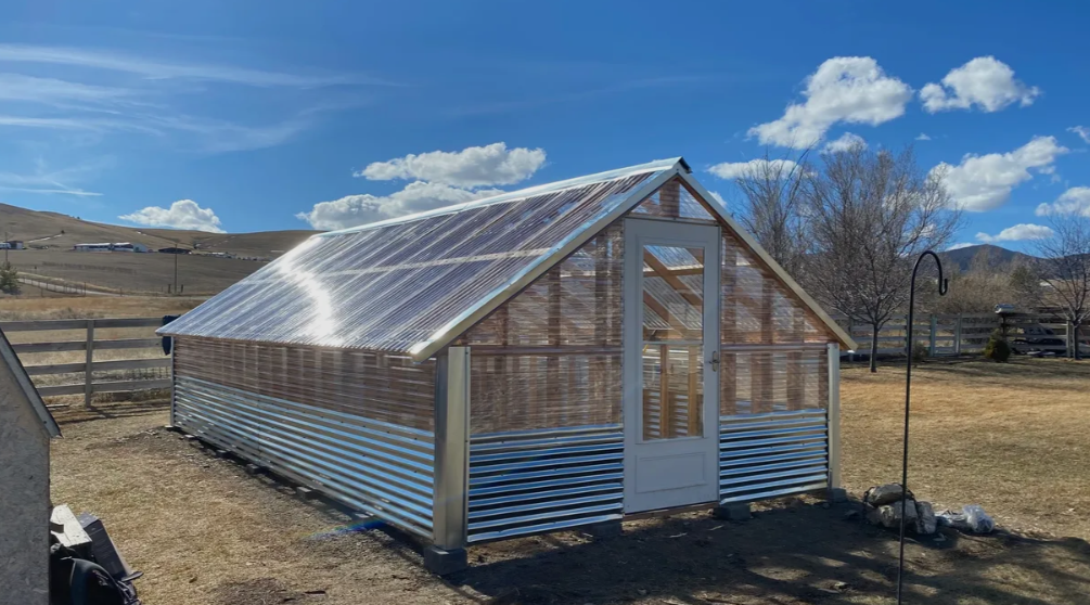 A greenhouse is sitting in the middle of a field.