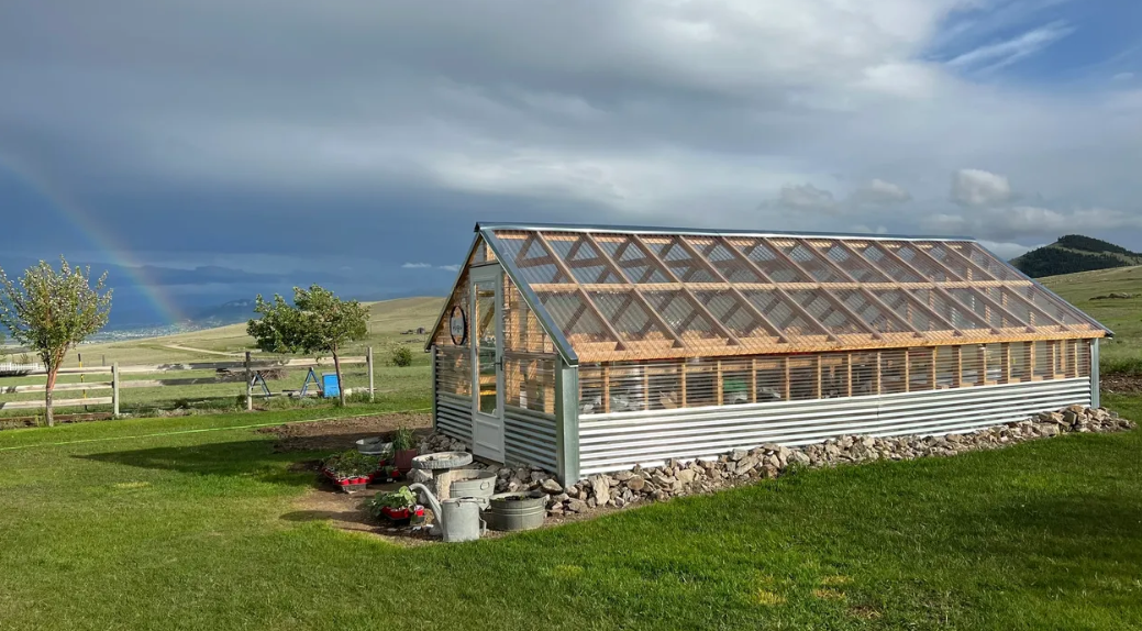 A greenhouse is sitting in the middle of a lush green field.