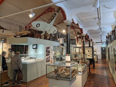 Museum interior, exhibits with display cases, aircraft model suspended from the ceiling.