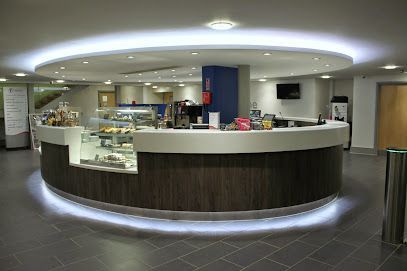 Cafe counter in a modern building with a curved design, wood paneling, and a glowing light.
