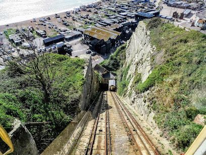 Elevated view of a funicular railway descending a steep cliff toward a coastal town and sea.