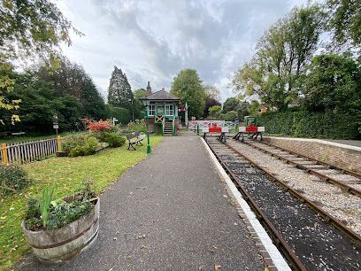Railroad platform with tracks, a signal box, and garden on an overcast day.