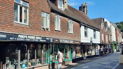 Row of shops on a street with pedestrians. Brick, white, and wood buildings under a blue sky.