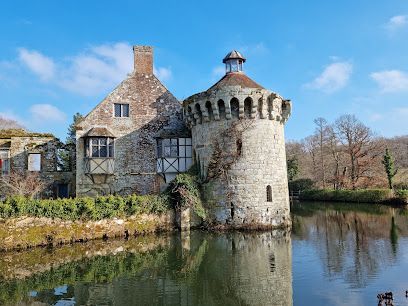 Stone castle with a round tower on water under a blue sky.