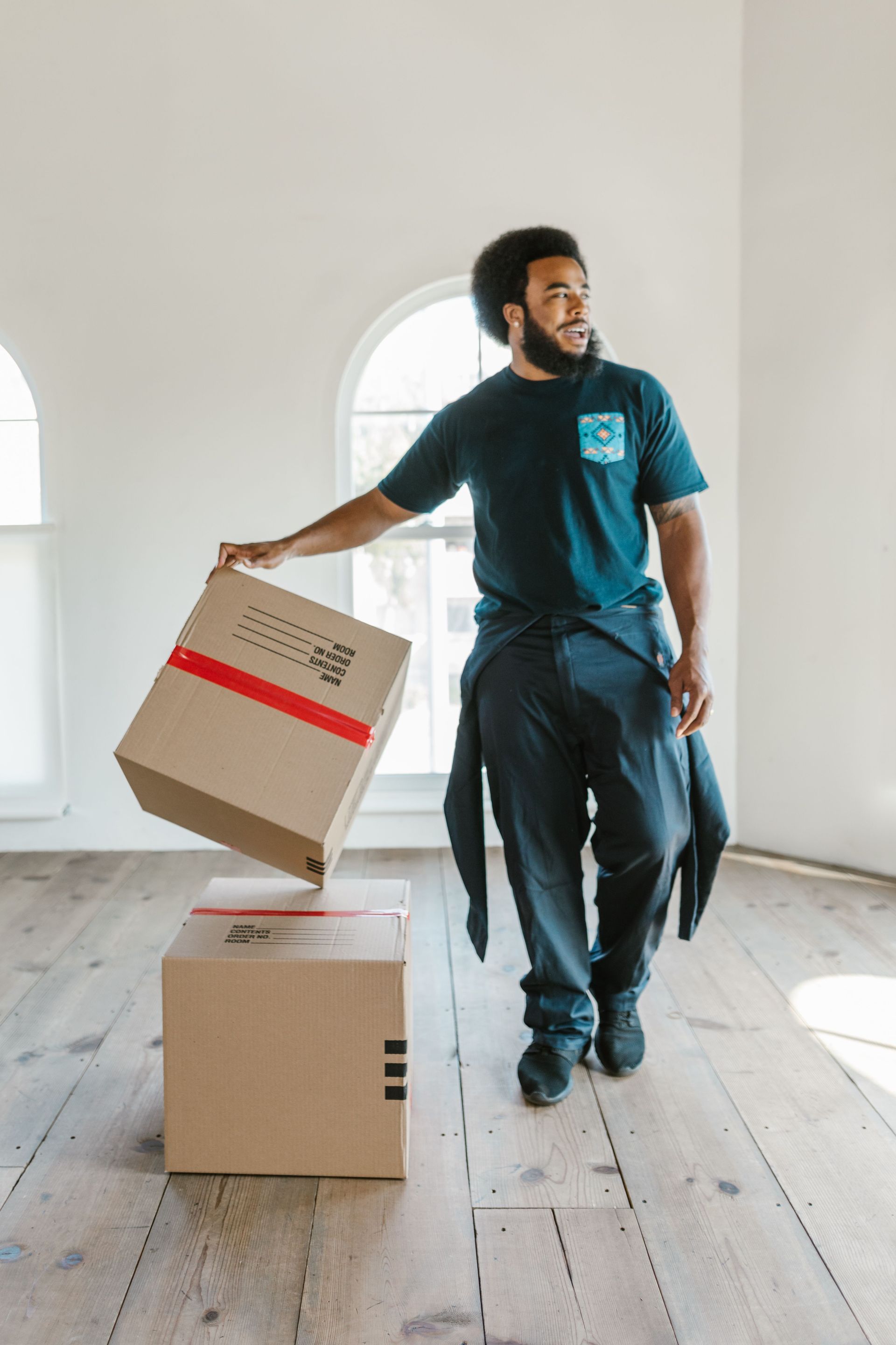 Man moving cardboard boxes in a bright empty room