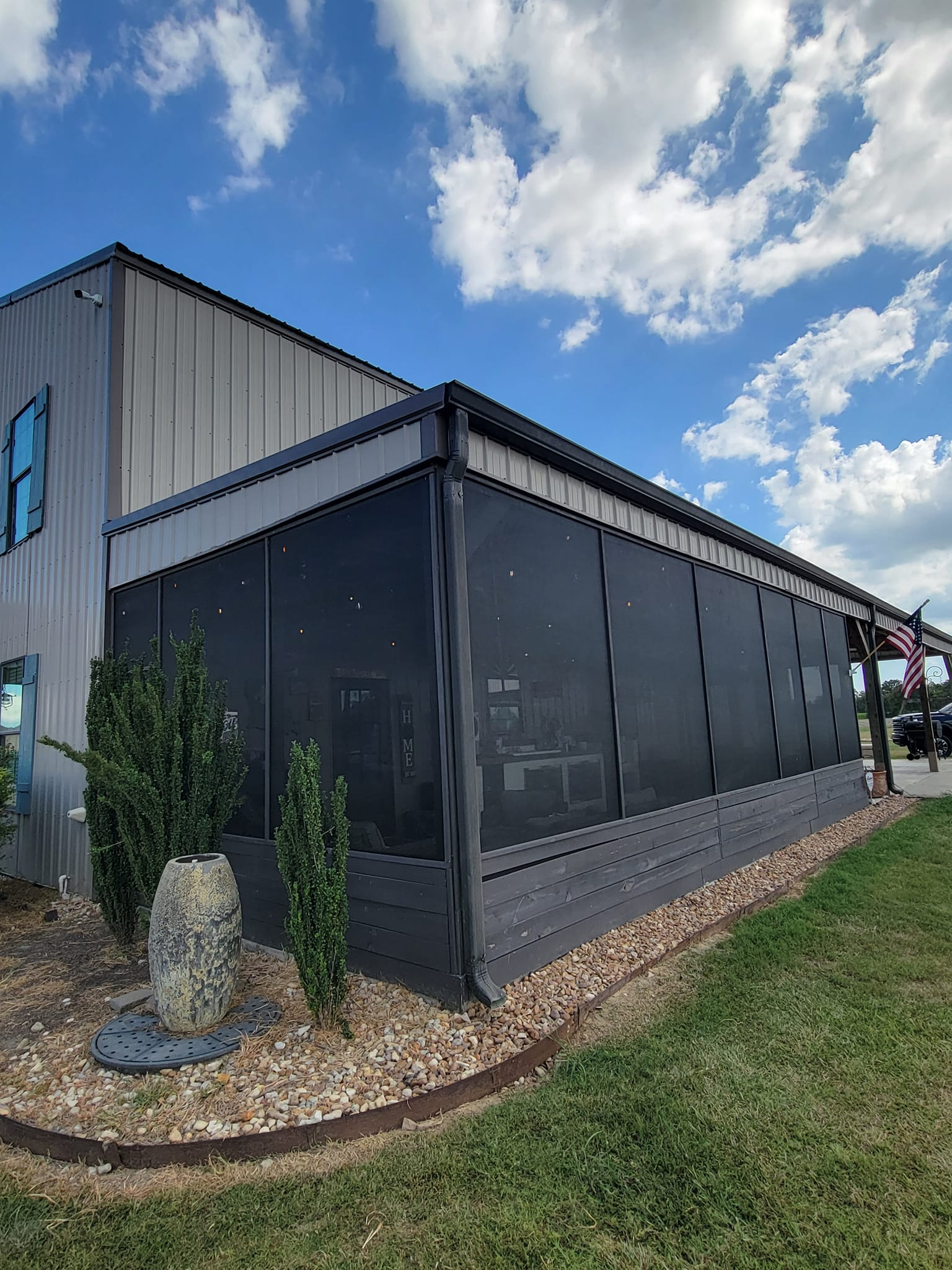 Building with dark gray screened enclosure and a blue sky.