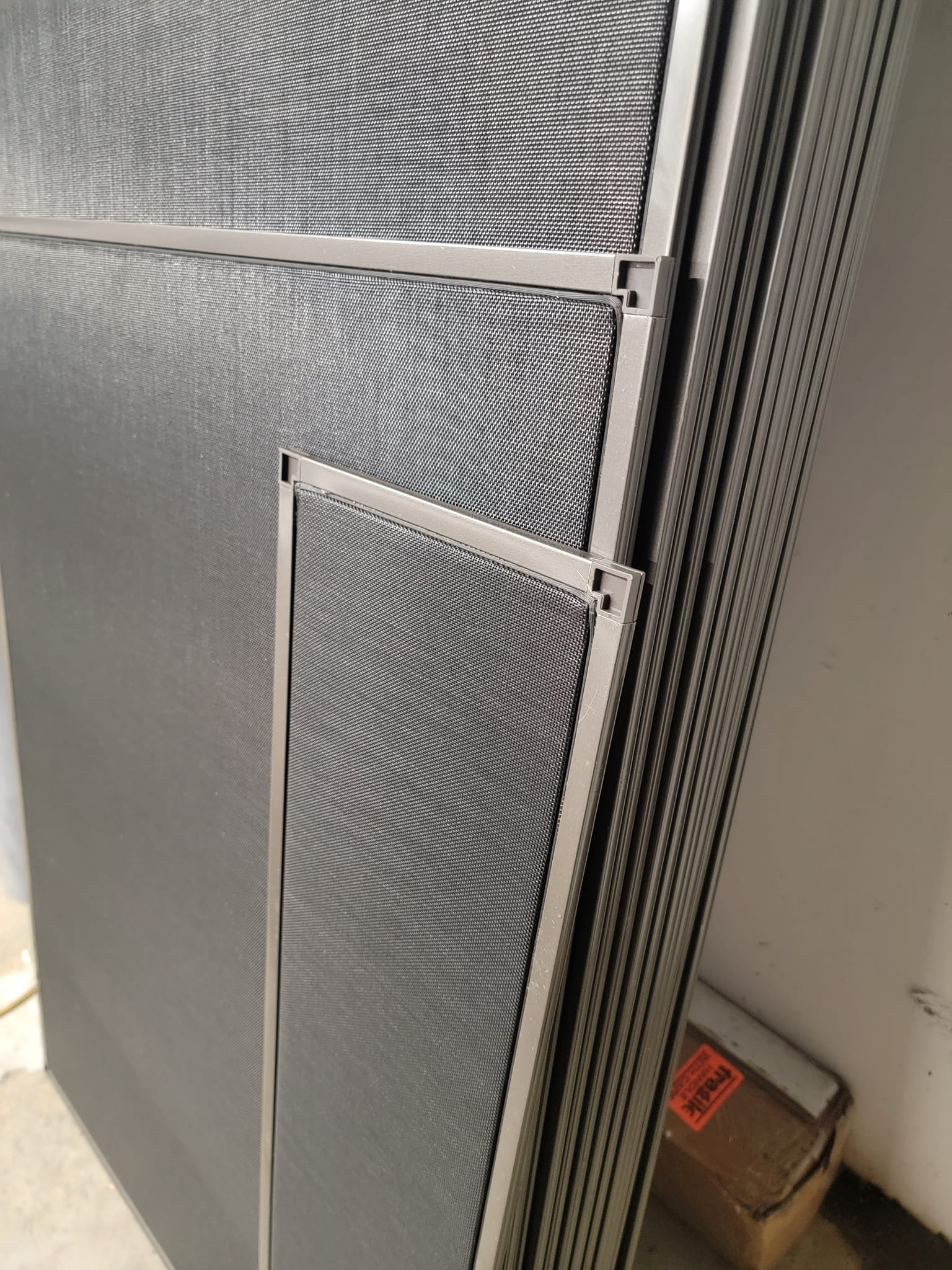 Stack of aluminum-framed window screens with black mesh.