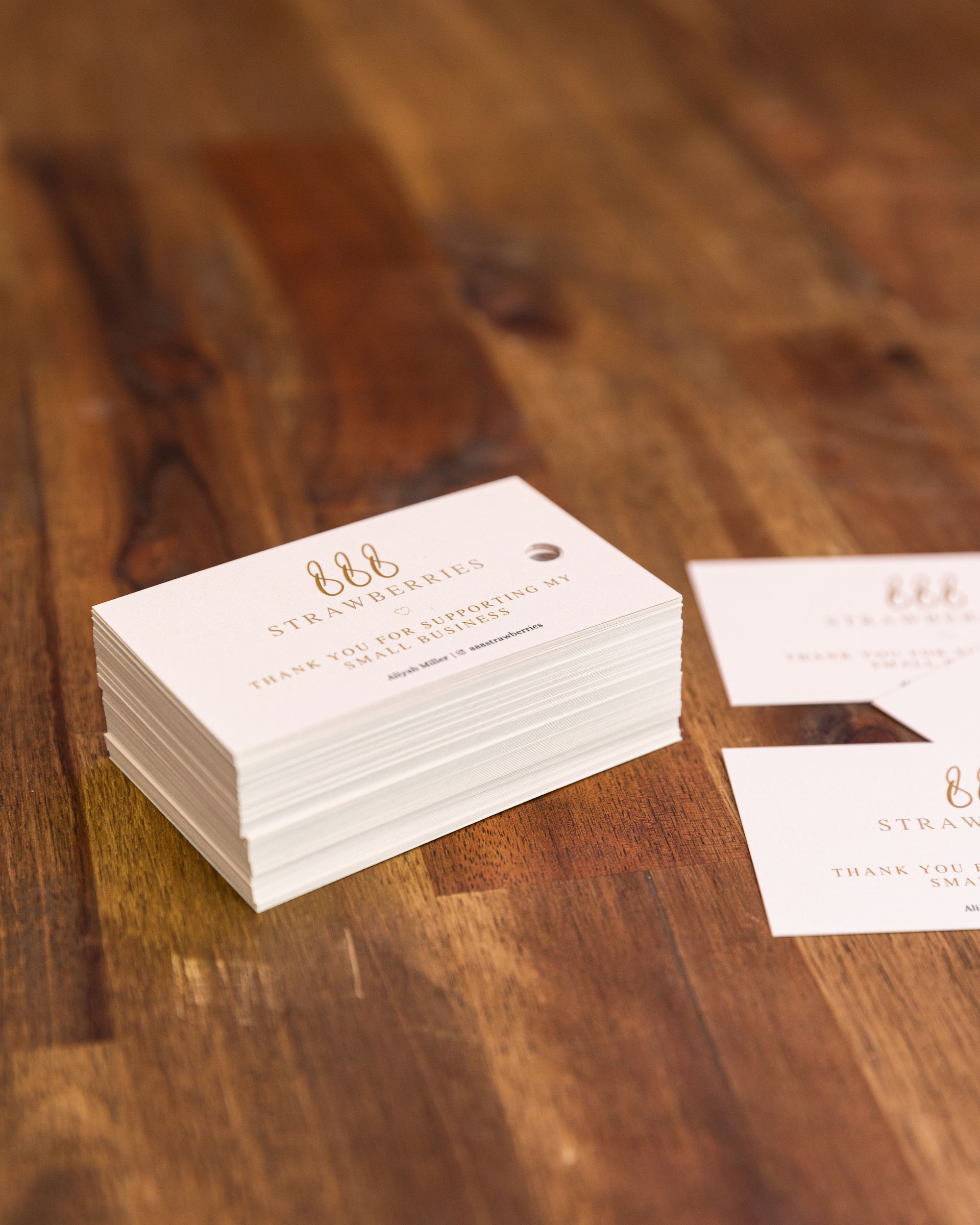 A stack of business cards sitting on top of a wooden table.