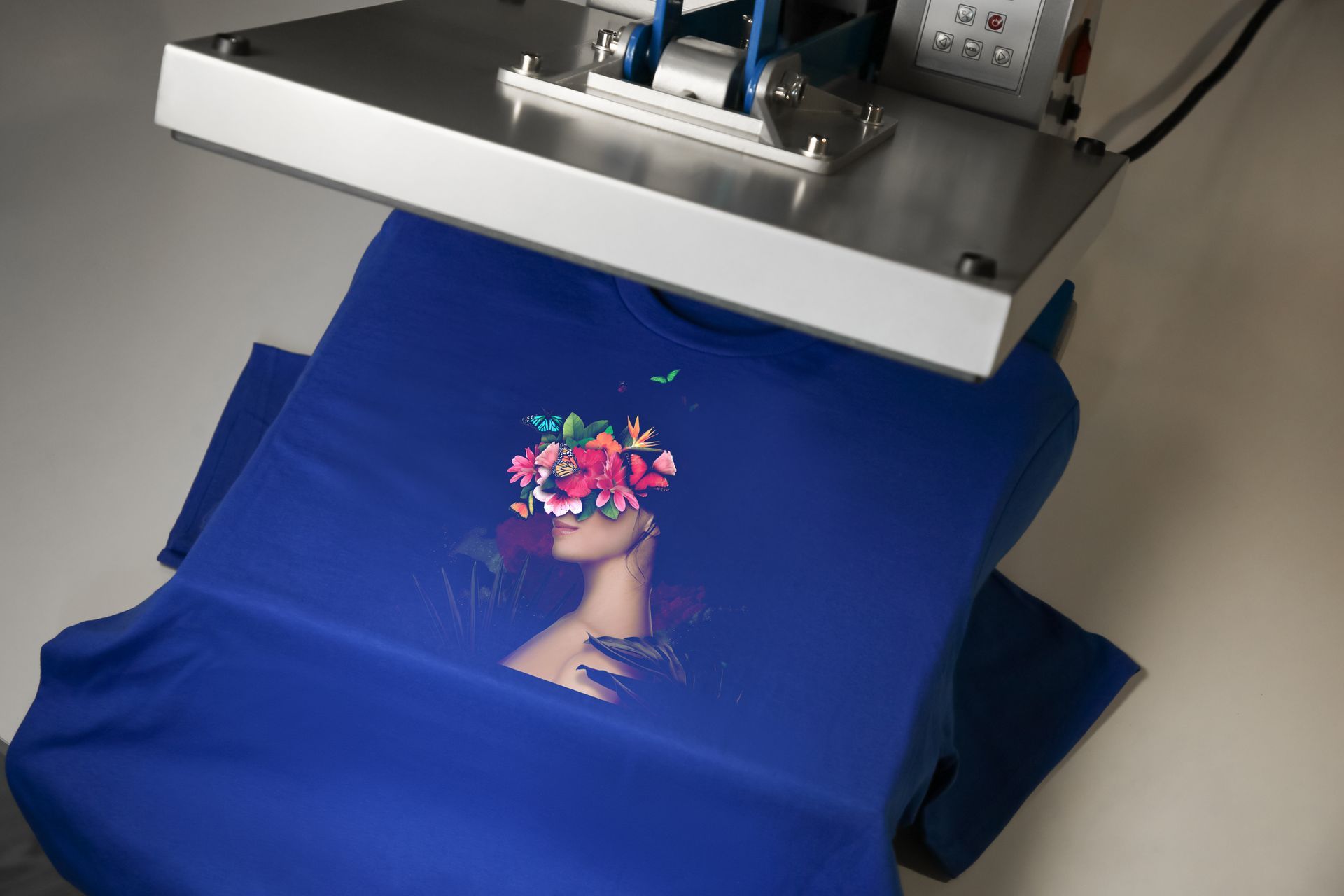 A blue shirt with a picture of a woman with flowers in her hair is being printed on a machine.