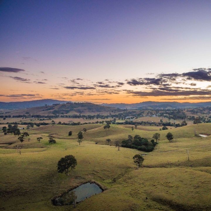 An Aerial View of a Lush Green Valley at Sunset With Mountains in the Background — Freedom Flooring Pty Ltd in Maitland, NSW