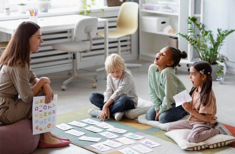 A woman is teaching a group of children while sitting on the floor.