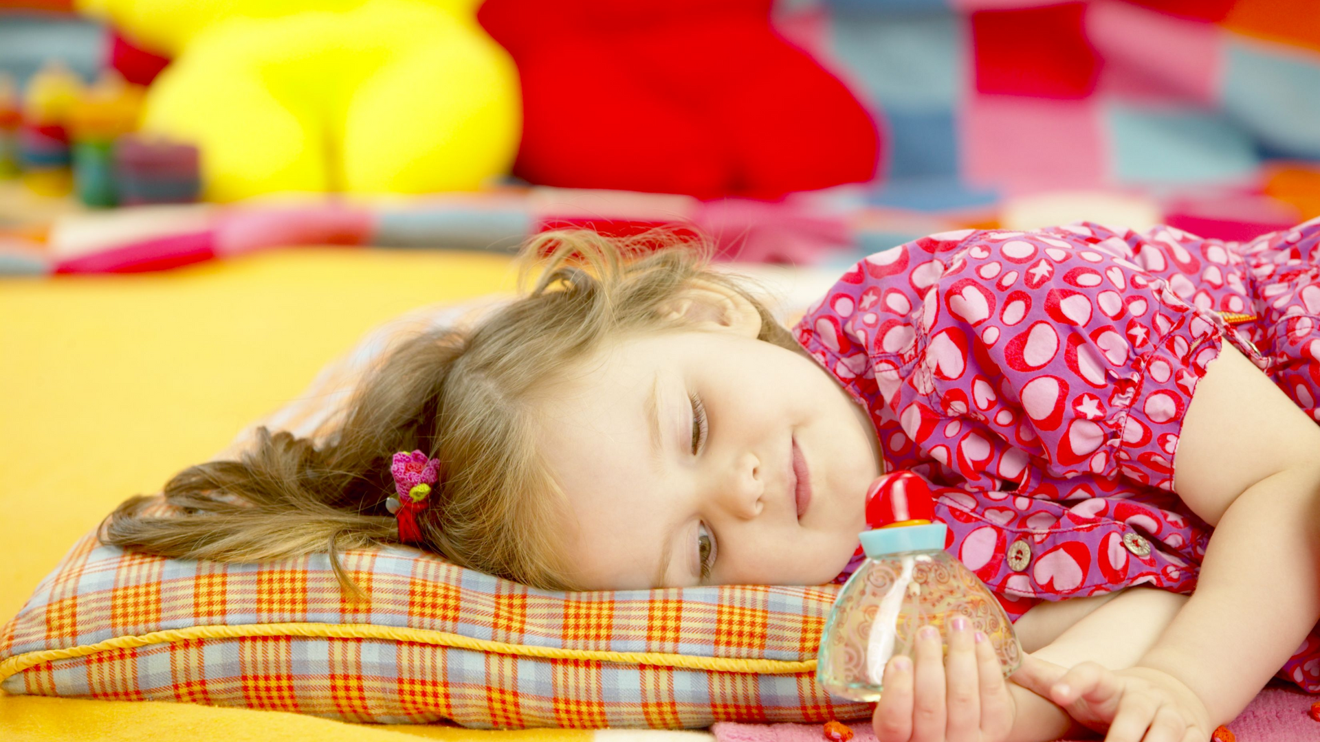 A little girl is sleeping on a pillow with a bottle of water.