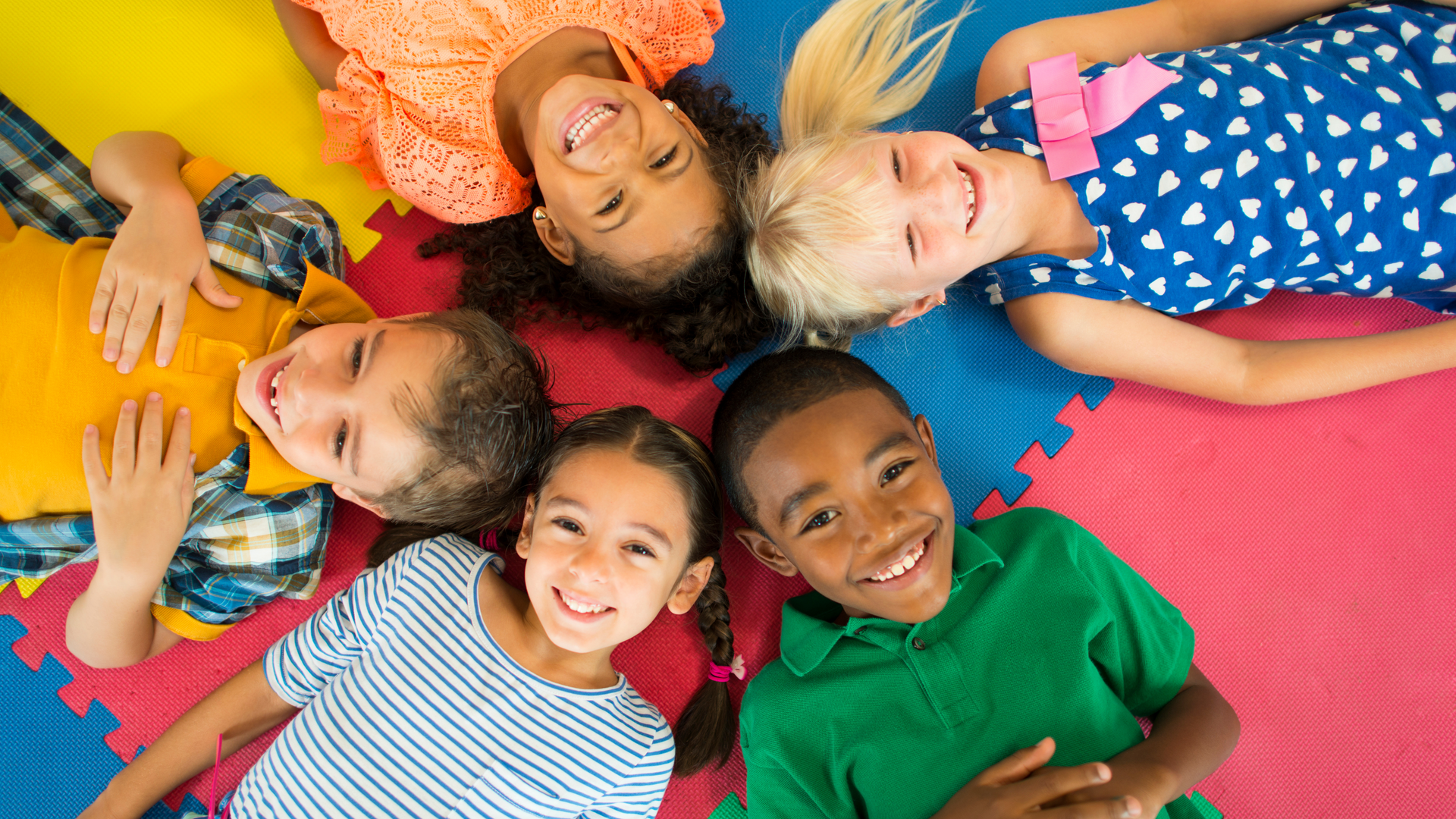 A group of children are laying on the floor in a circle.