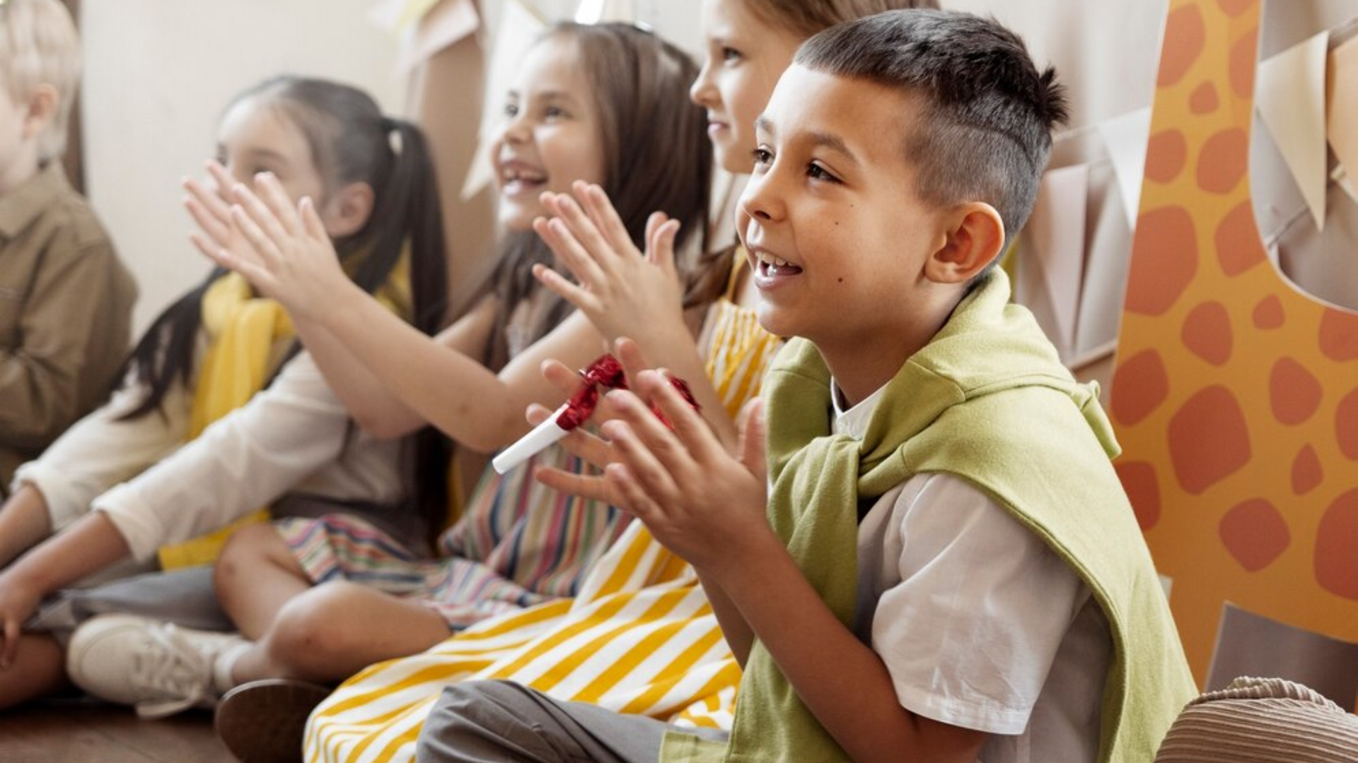A group of children are sitting on the floor clapping their hands.