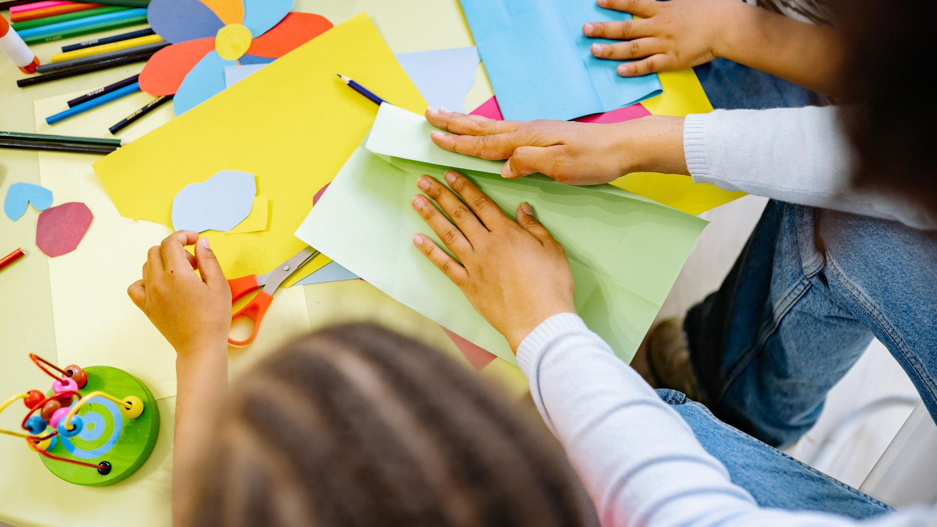 A group of children are sitting at a table making crafts.
