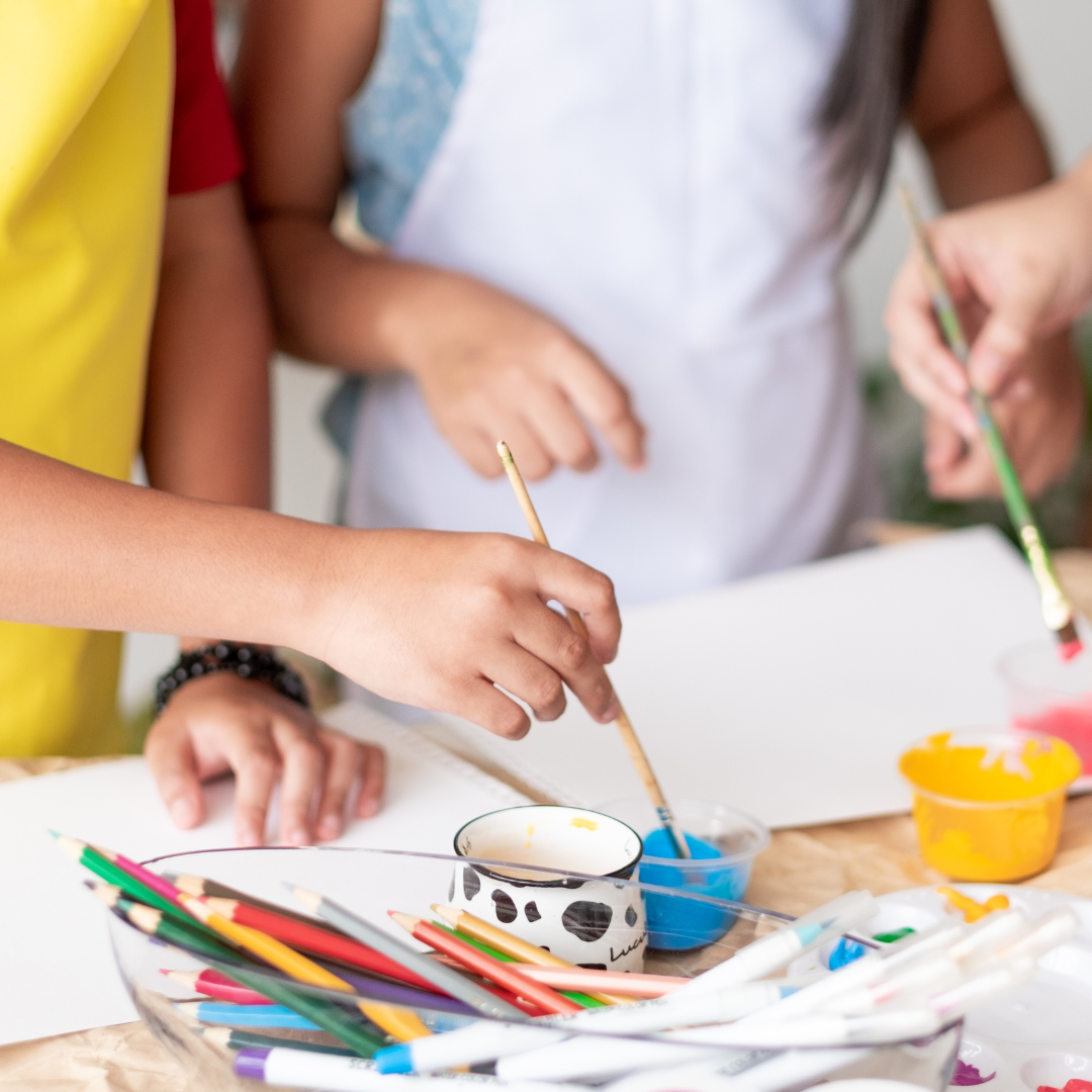 A group of children are painting on a piece of paper.