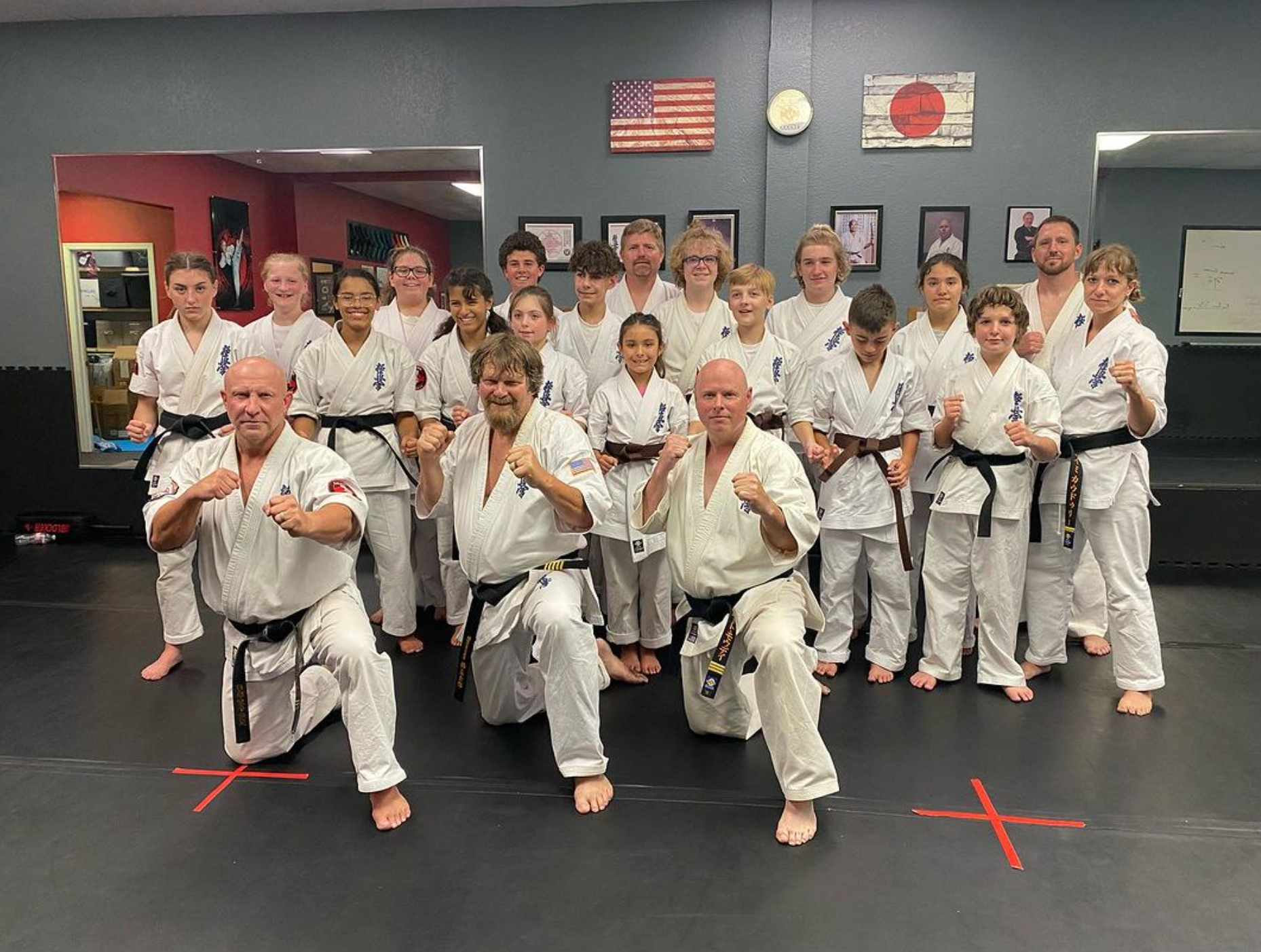 A group of people in karate uniforms are posing for a picture in a gym.