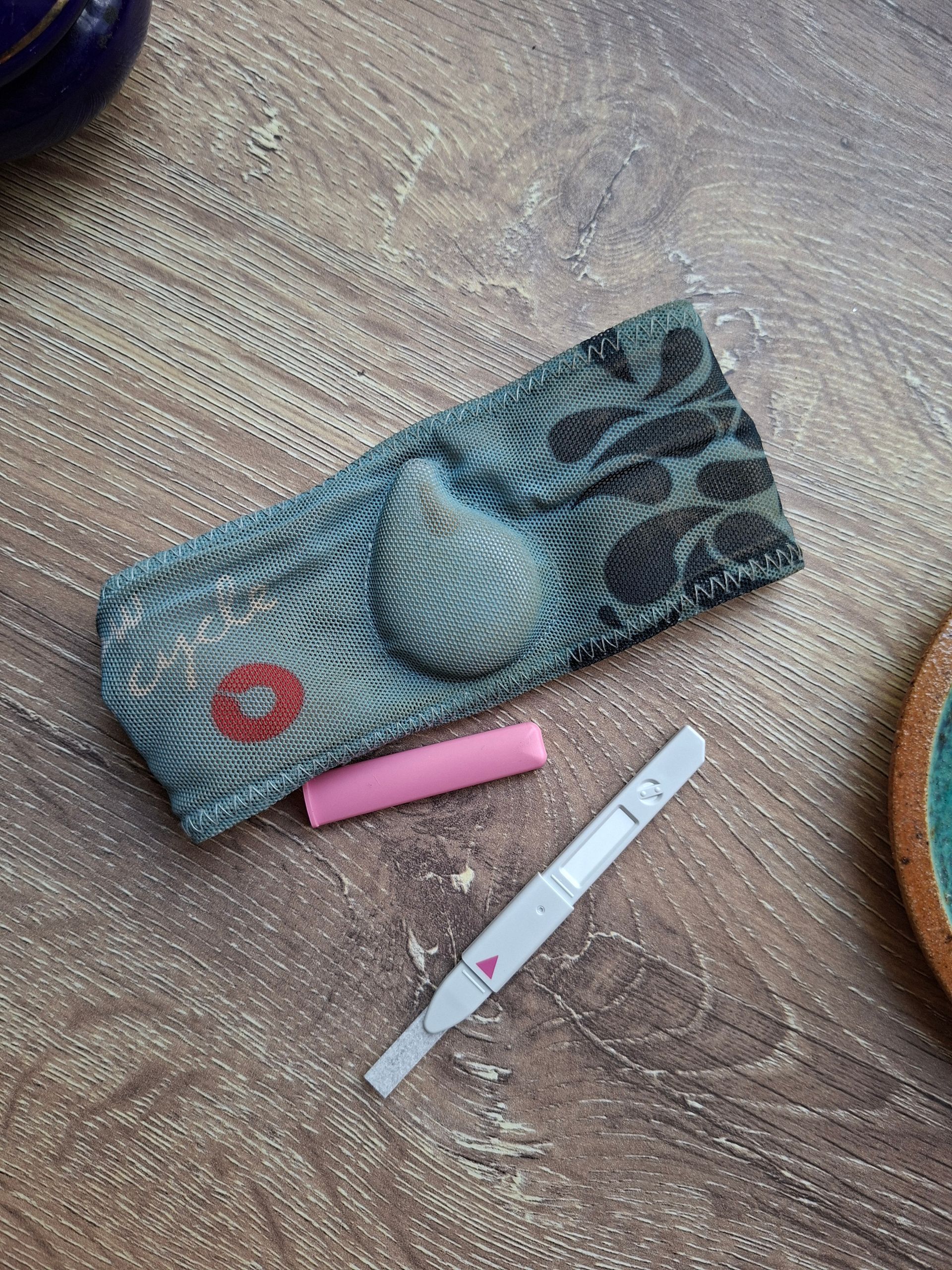 Pregnancy test and test cover on a wooden surface. Includes pink cap.