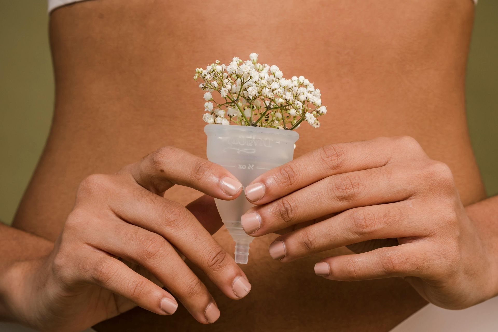 Woman holding a menstrual cup with flowers, representing menstrual cycle coaching and fertility awareness