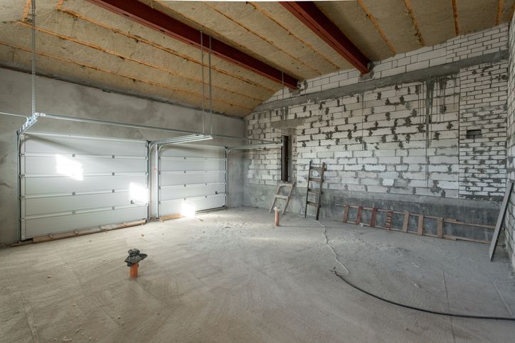 An empty garage with a garage door and a ladder.