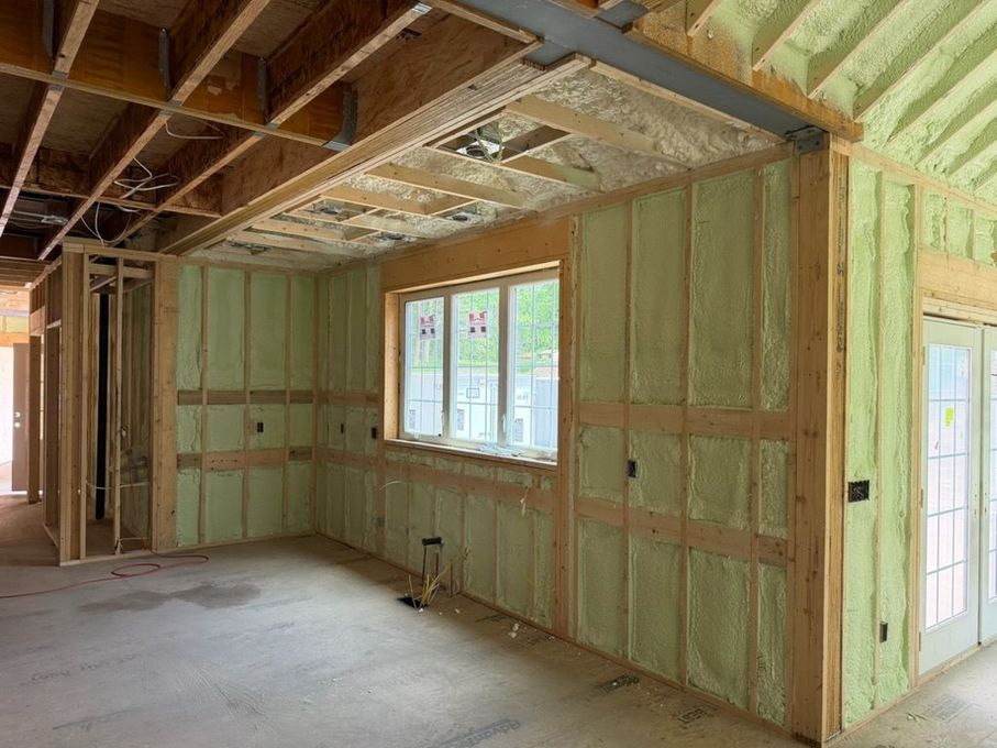 Unfinished room with exposed insulation, wood framing, and a window letting in daylight.