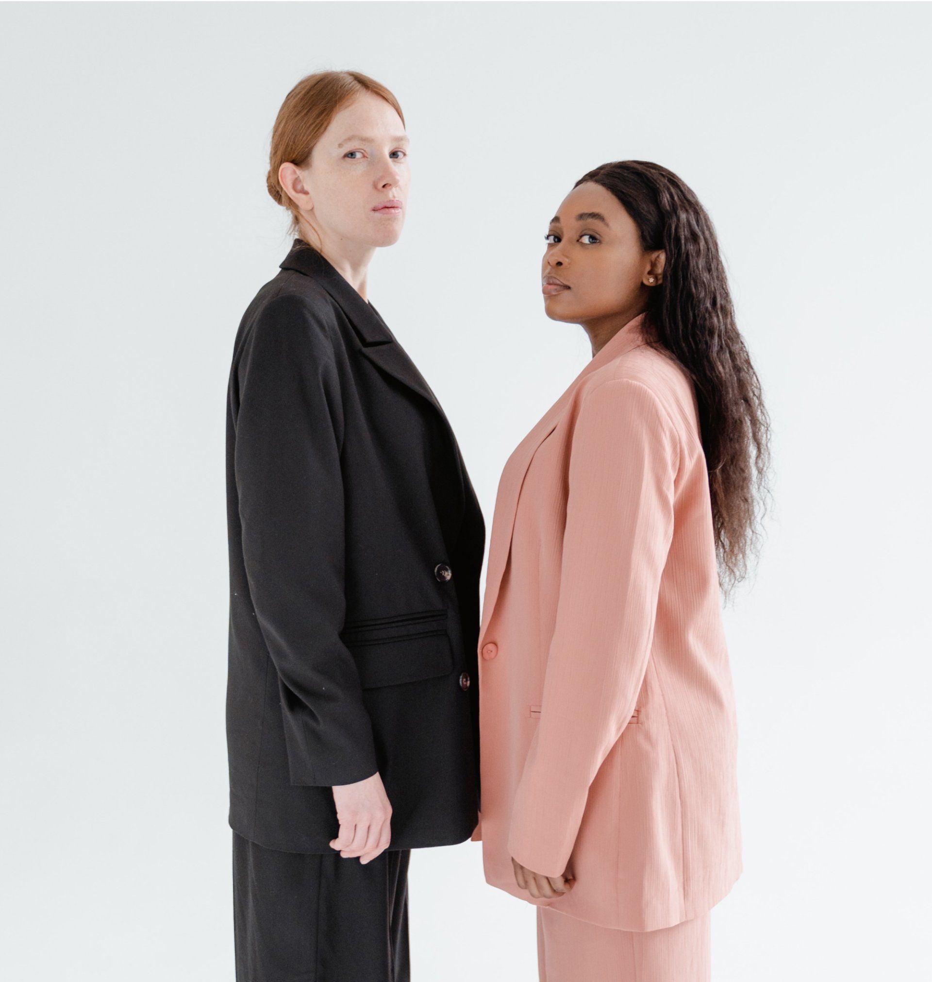 Two people in business suits standing face-to-face against a white background.