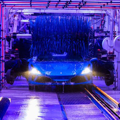 Car covered in blue foam at an automated car wash, lit by purple and blue lights