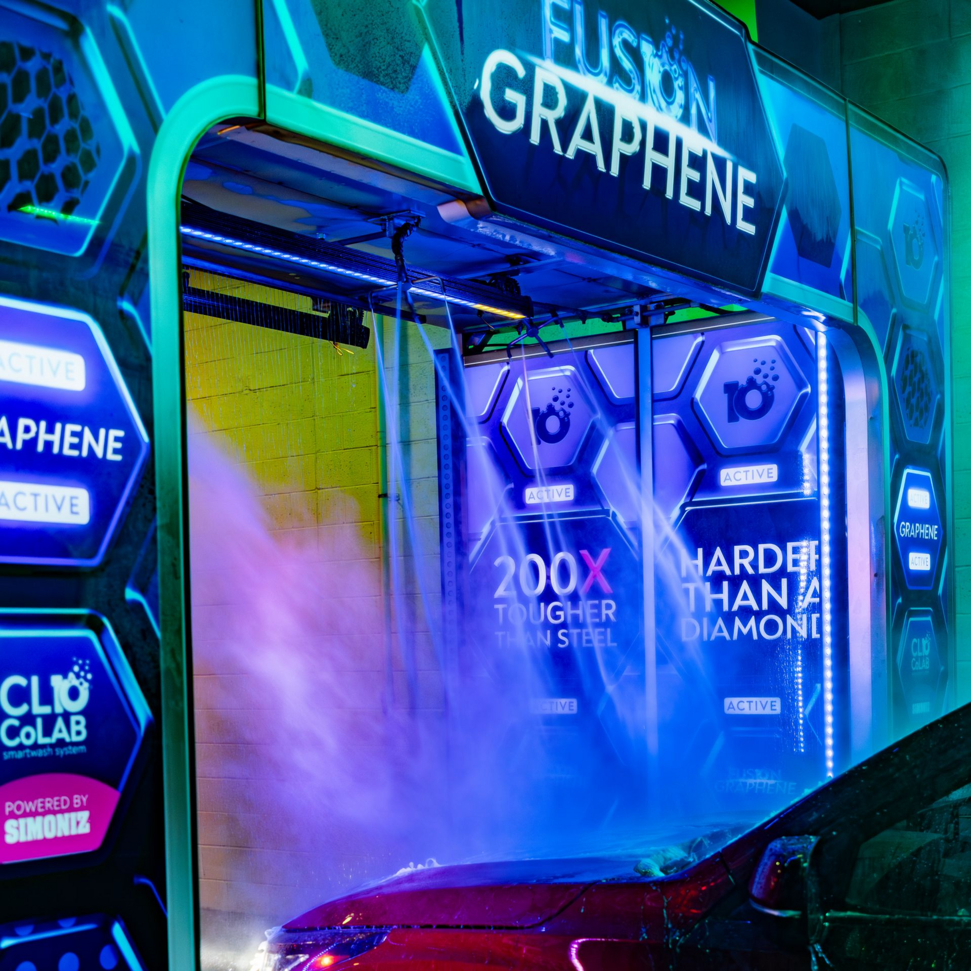 Rear view of a white truck driving through a neon-lit car wash at night, with water spraying around it