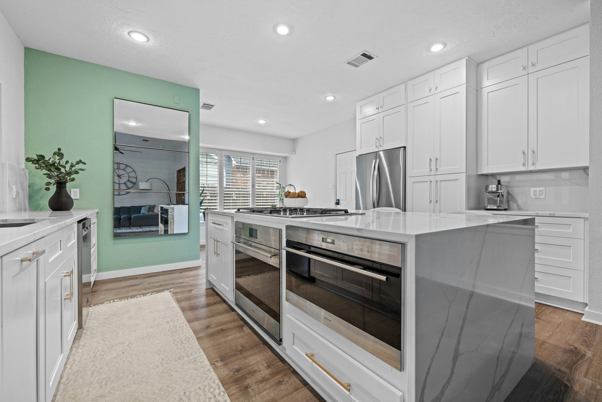 A kitchen with white cabinets , stainless steel appliances , and a large island.