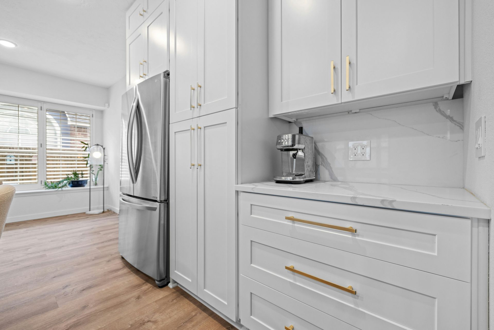 A kitchen with white cabinets and a stainless steel refrigerator.